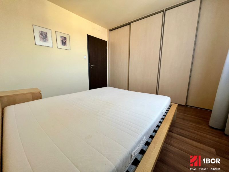 Schlafzimmer mit Doppelbett, Einbauschrank und Holzboden in einer Zweizimmerwohnung.
