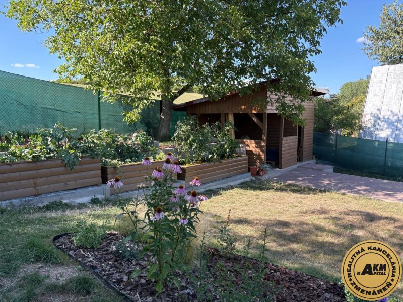 Gärten in Zvolen mit hölzernen Beeten und einem Pavillon, umgeben von Grün und Blumen.