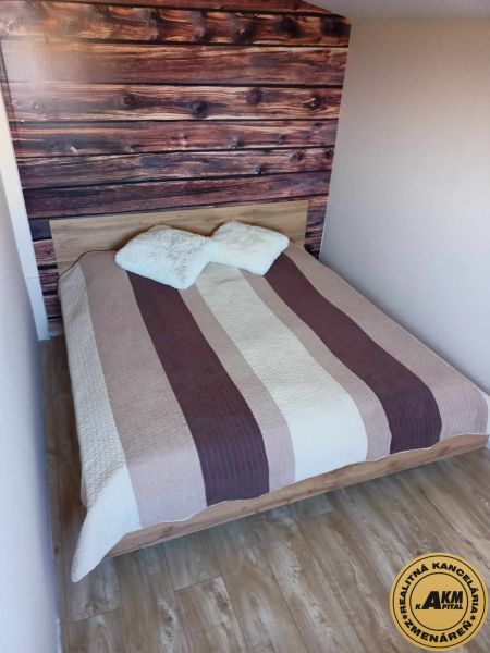 Ehebett mit gestreifter Überdecke und Boden in Holzoptik.