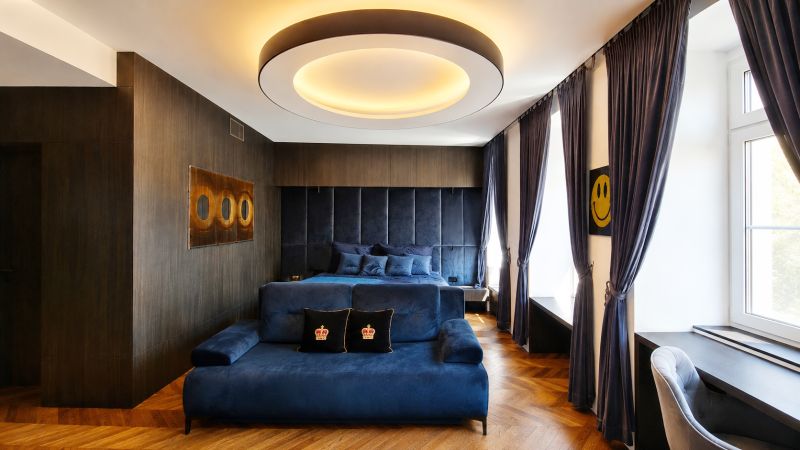 Luxuriöses Zimmer mit blauen Möbeln, Holzboden und großem Fenster.