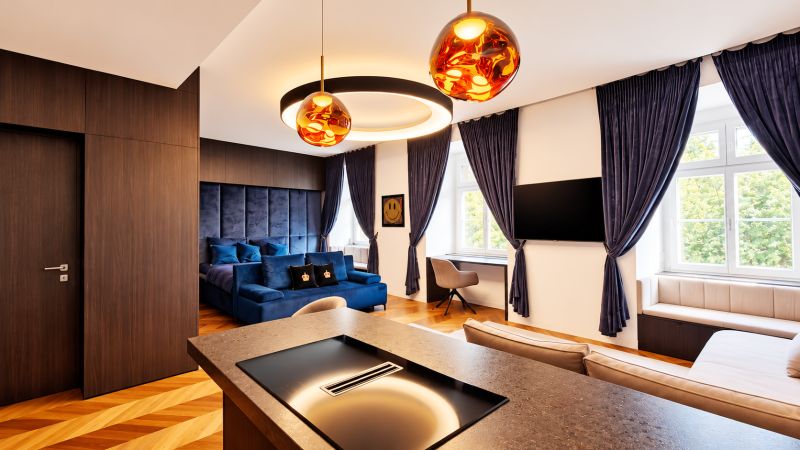 2-Zimmer-Wohnung mit Samtsofa, Holzelementen und Beleuchtung.
