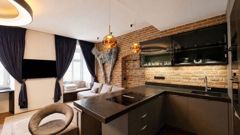 Küche in einer 2-Zimmer-Wohnung mit Ziegelwand und dunklen Vorhängen.