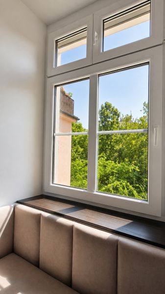 Helles Zimmer mit bequemen Sitzgelegenheiten und großem Fenster, 2-Zimmer-Wohnung.