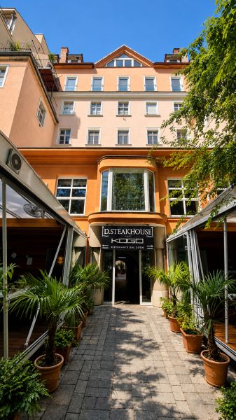 Ein Restaurant am Hviezdoslav-Platz in Bratislava - Altstadt, umgeben von Grün und Palmen.