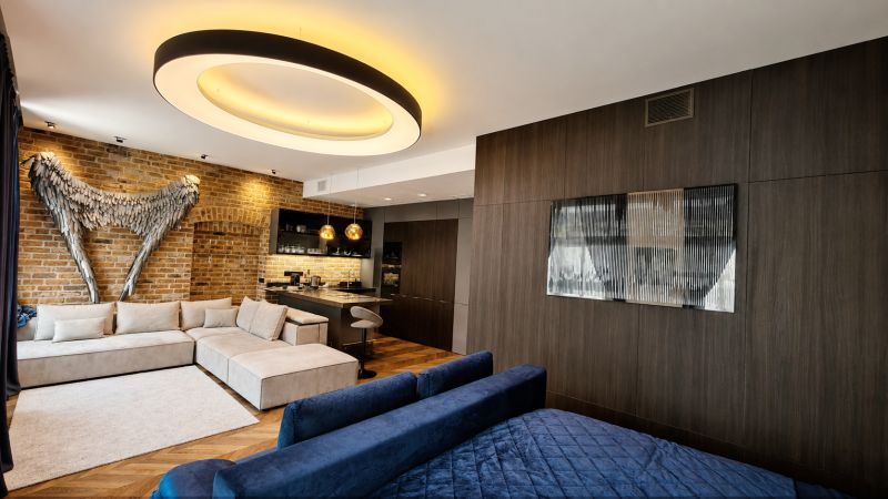 Ein mit Ziegeln, einem Sofa und moderner Beleuchtung dekorierter Raum, ergänzt durch einen Boden mit Holzdekor.