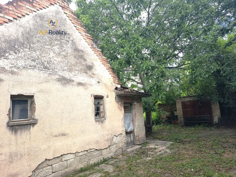 Ein älteres Familienhaus in Nové Zámky, umgeben von Grün, mit beschädigten Wänden.