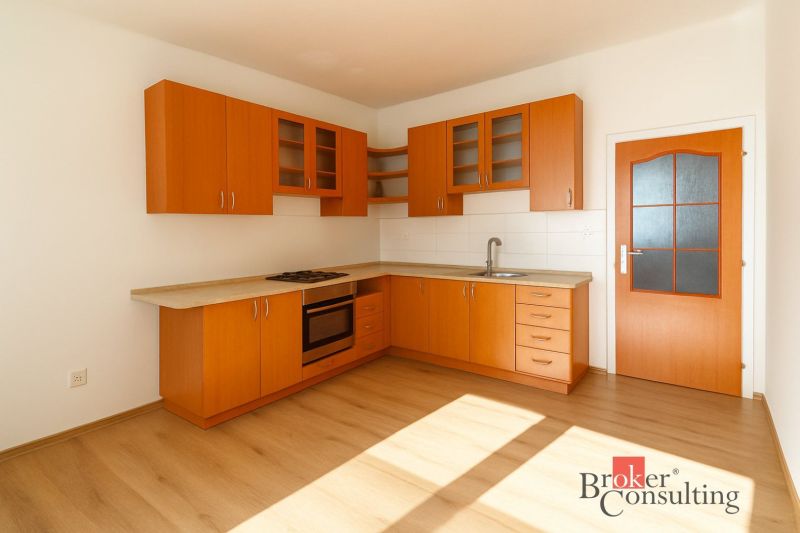 Küche in einer 2-Zimmer-Wohnung mit Holzschränken und einem Boden in Holzoptik.