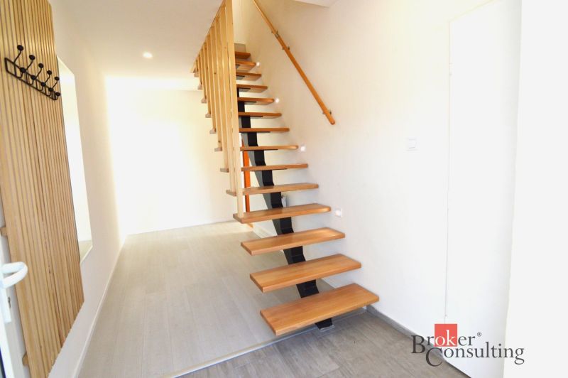 Flur in einer 2-Zimmer-Wohnung mit offener Treppe und Holzboden.