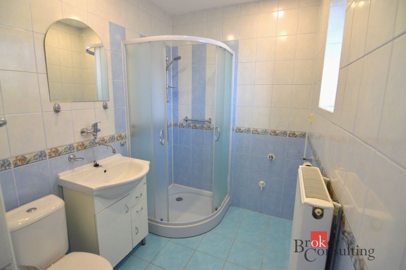 Badezimmer in einer 2-Zimmer-Wohnung mit blauen Fliesen, Duschkabine und Waschbecken.