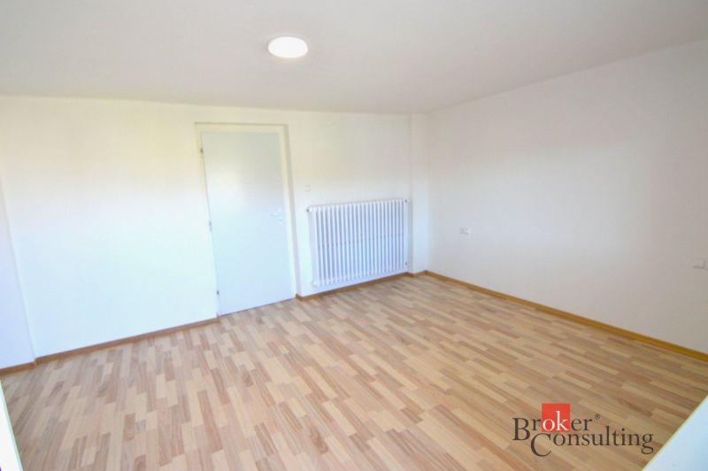 Ein Zimmer mit weißen Wänden und einem Boden in Holzoptik in einer Zweizimmerwohnung.