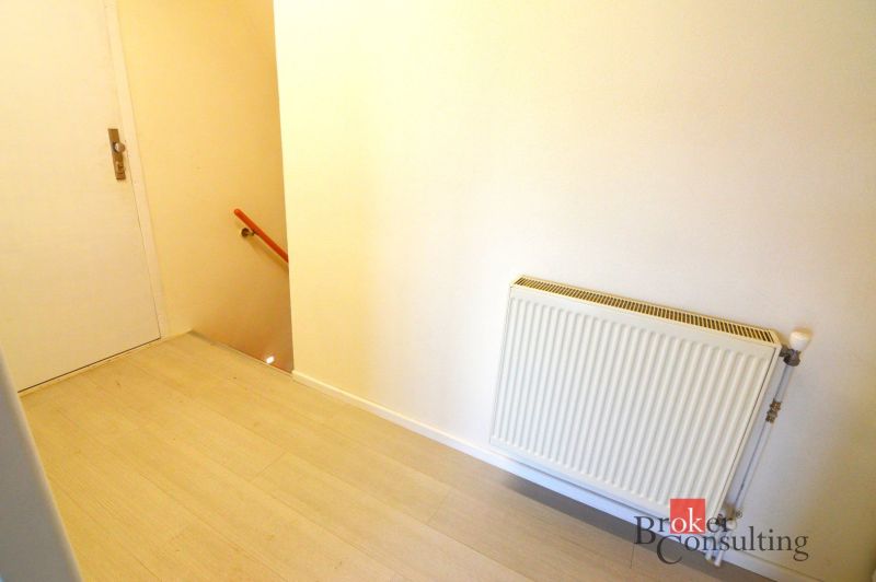 Flur mit Holzboden, Heizkörper und Treppe in einer 2-Zimmer-Wohnung.