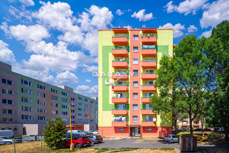 Bunte Wohnhäuser in der Sládkovičova-Straße in Fiľakovo mit Parkplatz und Grünflächen.
