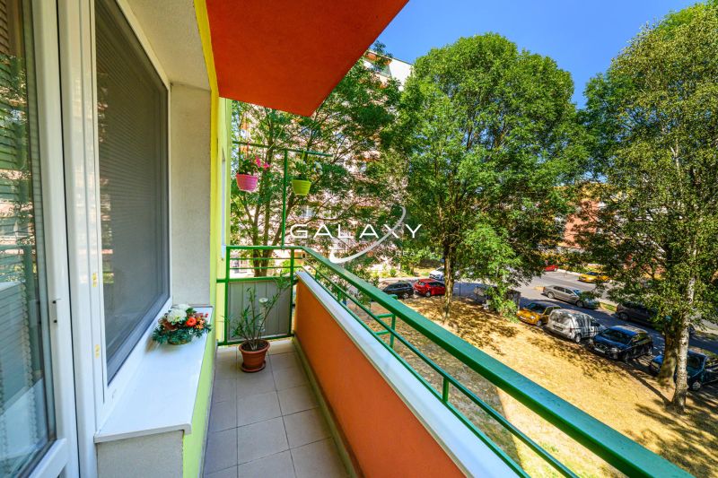 Der Balkon der 2-Zimmer-Wohnung in der Sládkovičova-Straße in Fiľakovo, gesäumt von Grün, mit Blumen.