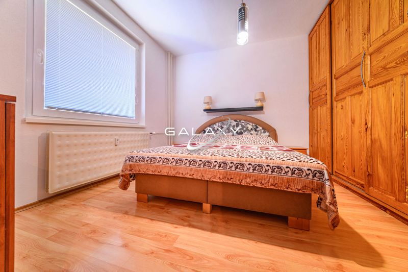 Schlafzimmer mit Kleiderschrank und Holzboden in einer Zweizimmerwohnung.