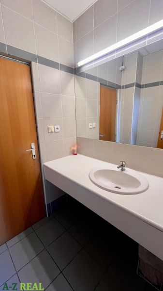 Ein Badezimmer mit Waschbecken, Spiegel und Holztüren im Büro.