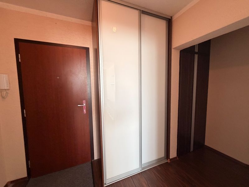 Eingangsbereich in einer 3-Zimmer-Wohnung mit einem weißen Kleiderschrank und einem Boden in Holzoptik.