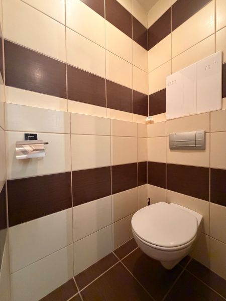 Toilette in einer 3-Zimmer-Wohnung mit braun-weißen Fliesen.