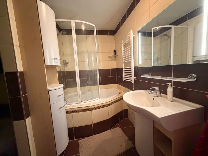 Badezimmer in einer 3-Zimmer-Wohnung mit Badewanne, Dusche, Waschbecken und Möbeln.