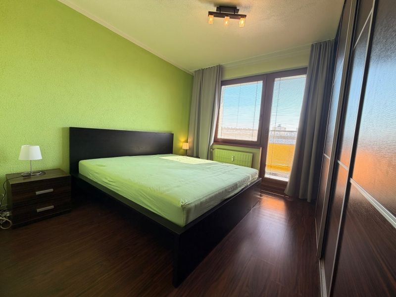 Schlafzimmer in einer 3-Zimmer-Wohnung mit Holzboden und grünen Wänden.