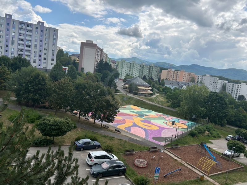 Blick auf einen bunten Spielplatz, einen Spielplatz und Plattenbauten in der Mateja Bela in Trenčín.