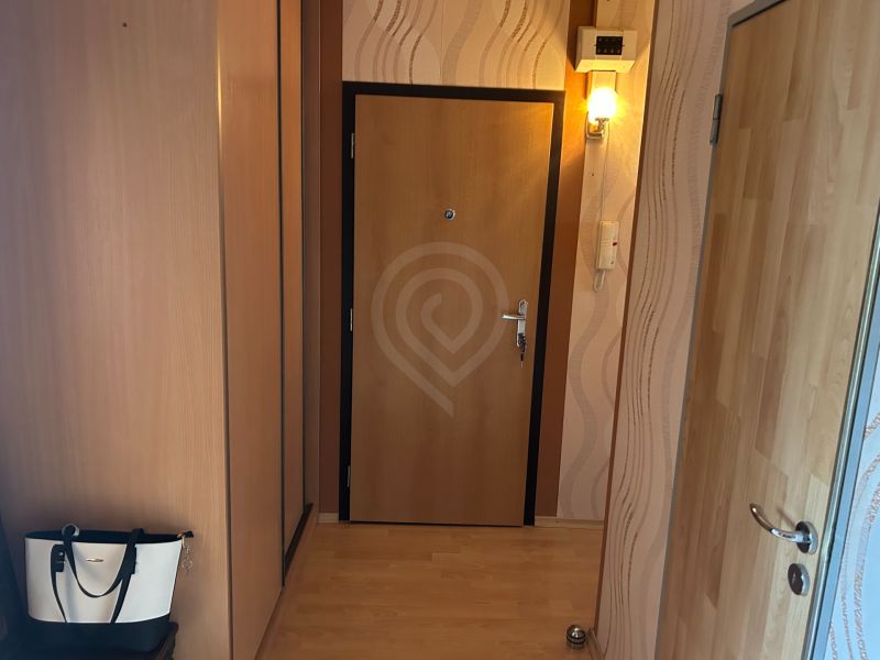 Flur in einer 3-Zimmer-Wohnung mit Holzboden und einer Wandleuchte.
