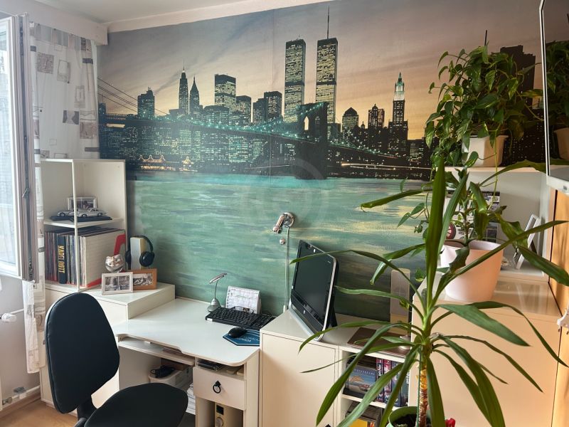Arbeitsbereich mit Schreibtisch, Pflanzen und dekorativer Tapete in einer 3-Zimmer-Wohnung.