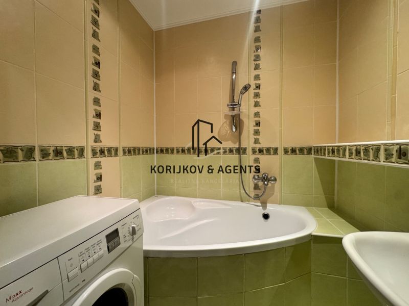 Badezimmer in einer 4-Zimmer-Wohnung mit Badewanne und Waschmaschine, grün-cremefarbene Fliesen.