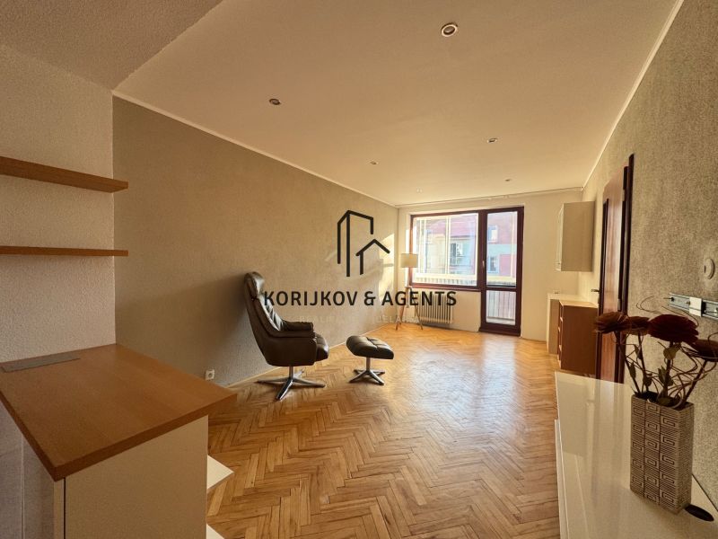 Wohnzimmer in einer Vierzimmerwohnung mit Holzboden und einem bequemen Sessel.