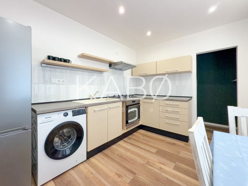 Küche in einer 2-Zimmer-Wohnung mit Holzboden, hellen Möbeln und Geräten.