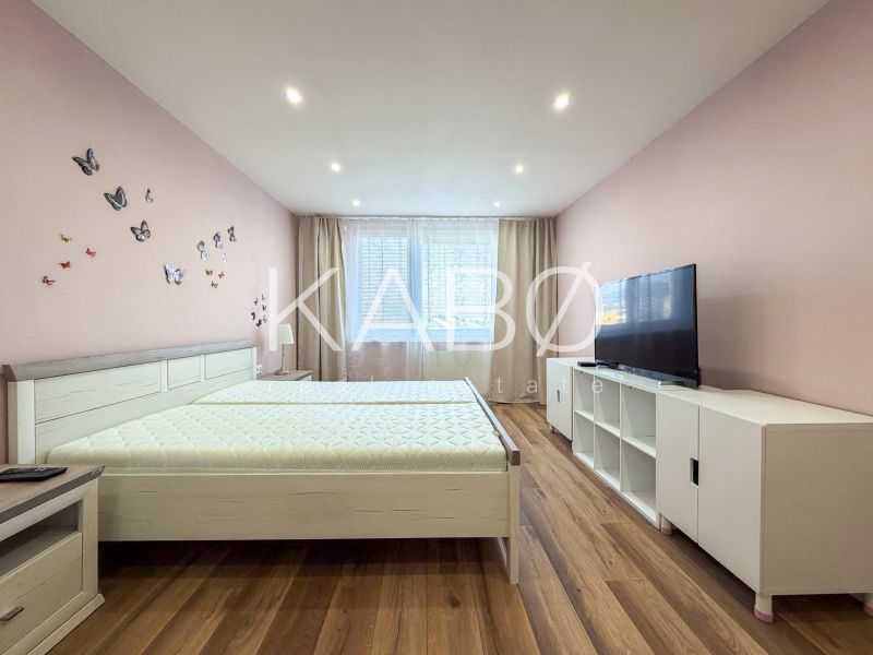 Helles Schlafzimmer mit Schmetterlingen an der Wand und einem Boden mit Holzdekor in einer 2-Zimmer-Wohnung.