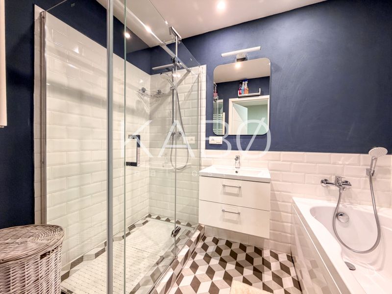 Badezimmer in einer 2-Zimmer-Wohnung mit Badewanne, Dusche und Designerfliesen.