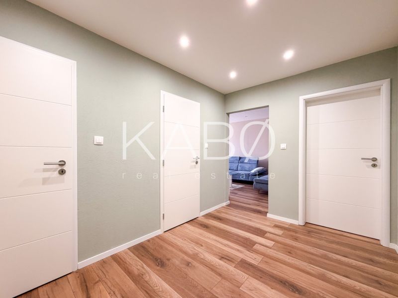 Der Flur in einer 2-Zimmer-Wohnung mit einem Boden in Holzoptik und weißen Türen.