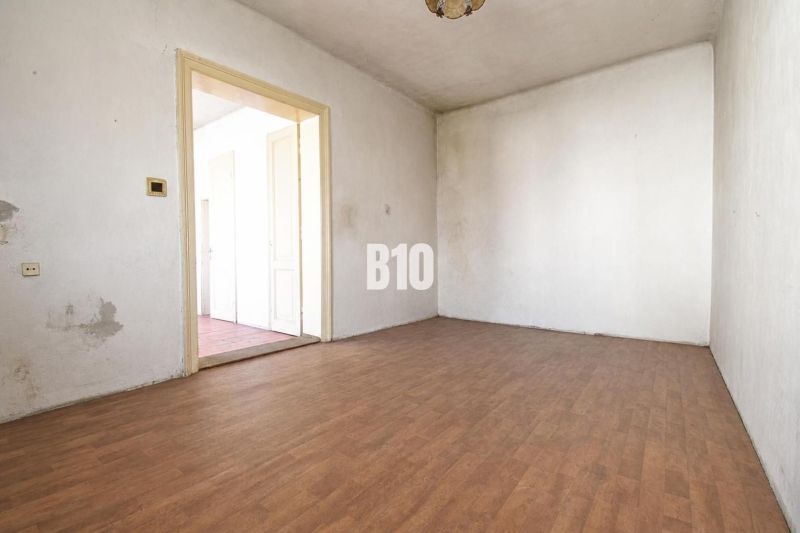 Ein Zimmer in einem Einfamilienhaus mit weißen Wänden und einem Boden in Holzoptik.