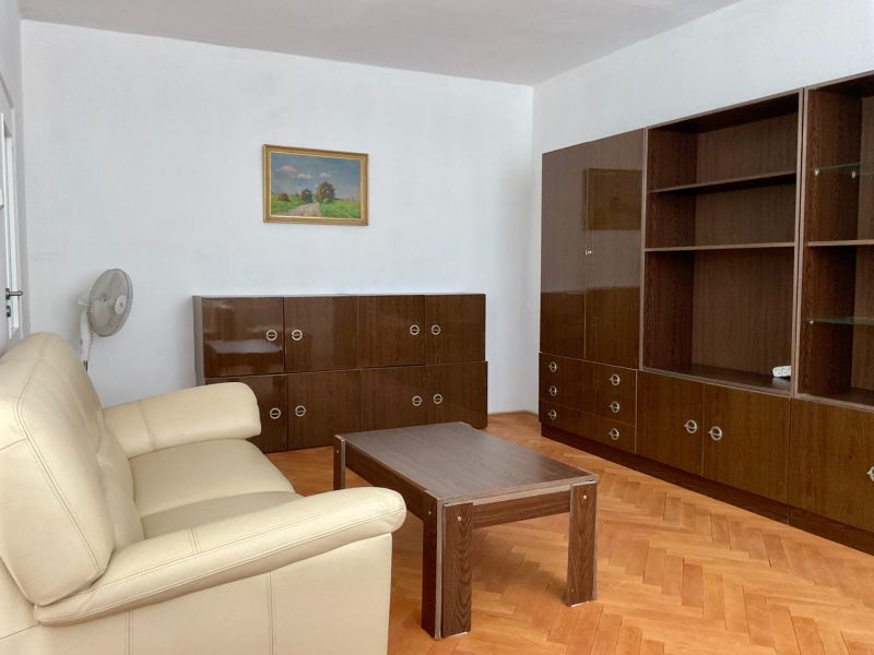 Wohnzimmer in einer 2-Zimmer-Wohnung mit Holzboden, Sofa und Schränken.
