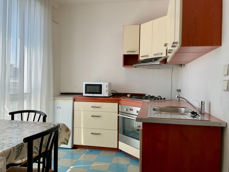 Küche in einer 2-Zimmer-Wohnung mit Mikrowelle, Herd und Esstisch.