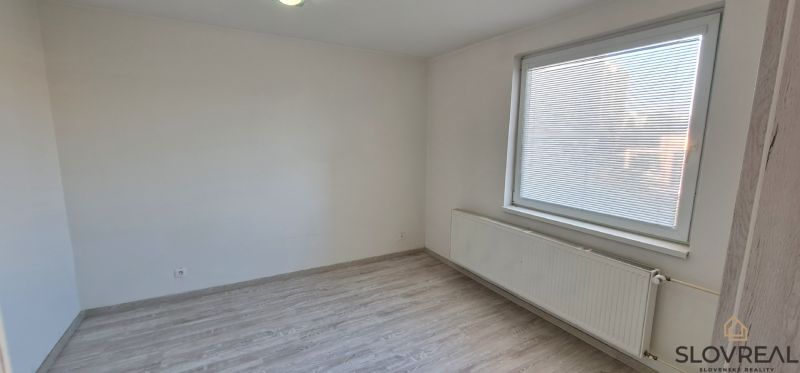Ein Zimmer in einer 2-Zimmer-Wohnung mit weißen Wänden und einem Boden in Holzoptik.