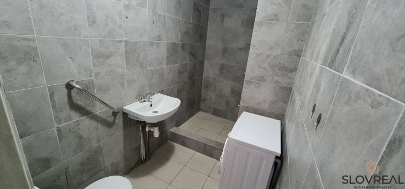 Badezimmer mit Fliesen, Waschbecken, WC und Waschmaschine in einer 2-Zimmer-Wohnung.