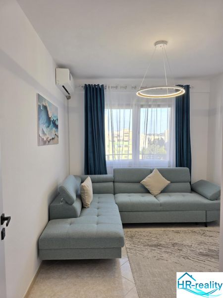Wohnzimmer in einer 2-Zimmer-Wohnung mit einem bequemen Sofa und stilvoller Beleuchtung.