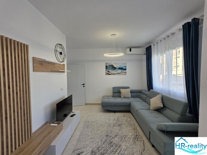 Wohnzimmer in einer 2-Zimmer-Wohnung mit Sofa, Fernseher und Holzdekor.