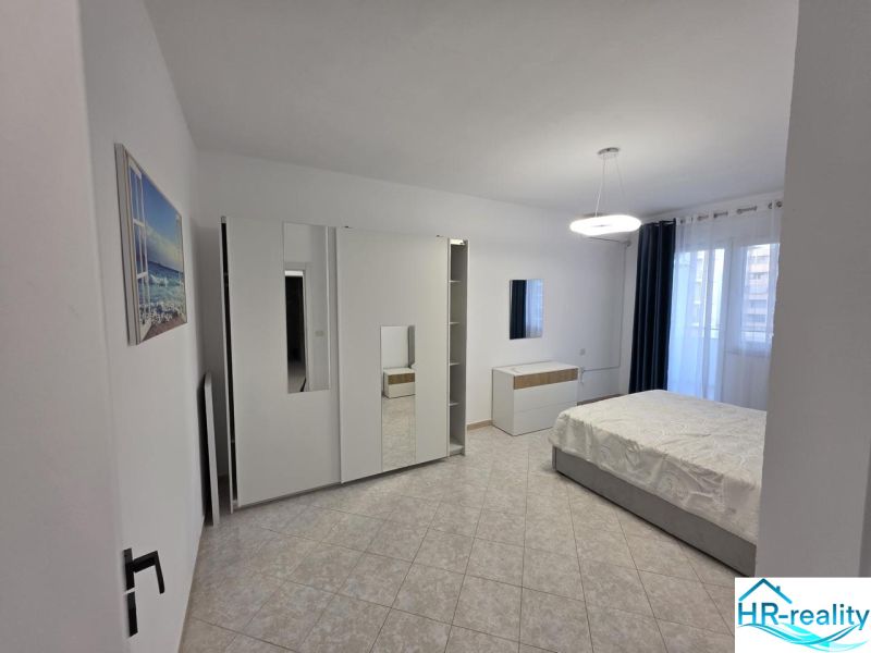 Helles Schlafzimmer in einer 2-Zimmer-Wohnung mit großem Kleiderschrank und Fliesenboden.