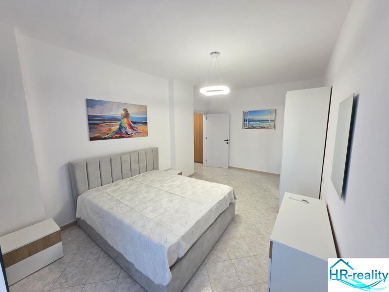 Helles Schlafzimmer in einer 2-Zimmer-Wohnung mit Kunstgemälden und weißen Möbeln.