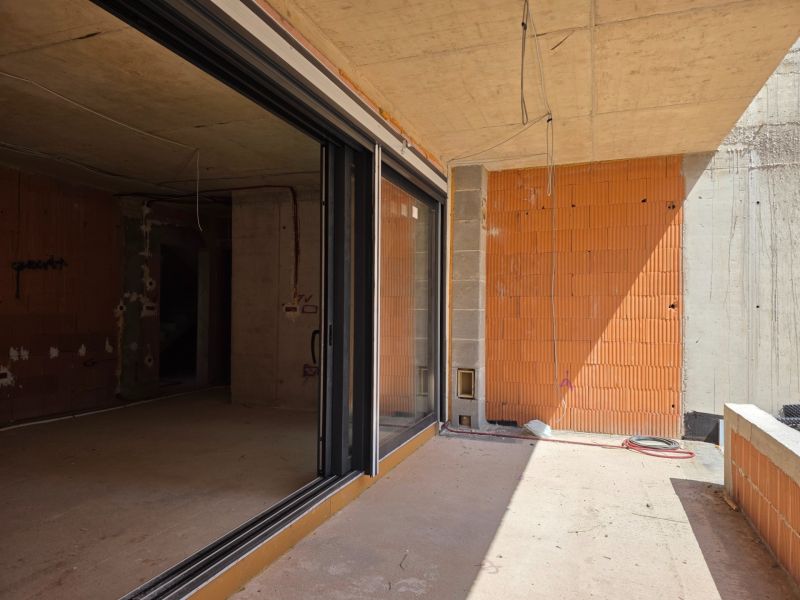 Unvollendete 3-Zimmer-Wohnung in SRIMA mit Glastüren und unverputzten Ziegelwänden.