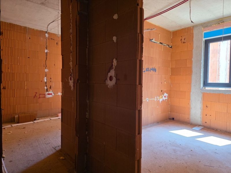 Innenraum einer 3-Zimmer-Wohnung mit Ziegelwänden, im Rohbau.