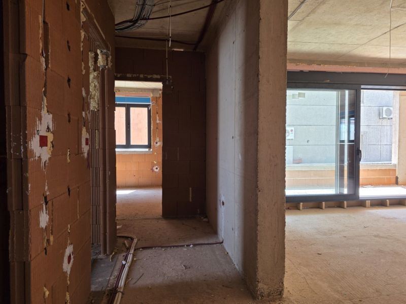 Unvollendetes Interieur einer 3-Zimmer-Wohnung mit großen Glastüren und Mauerwerk.