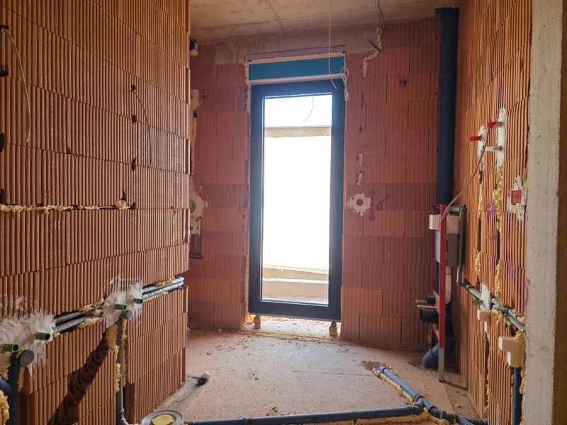 Ein unvollendeter Raum mit rohen Ziegelwänden und einem Ausgang zum Balkon in einer 3-Zimmer-Wohnung.