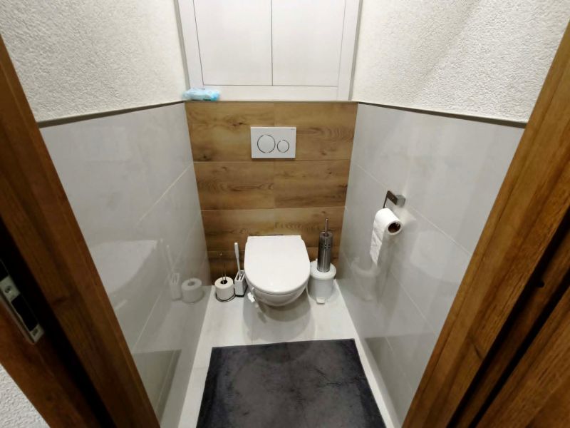 Toilette mit Holzboden und weißen Fliesen in einer 3-Zimmer-Wohnung.