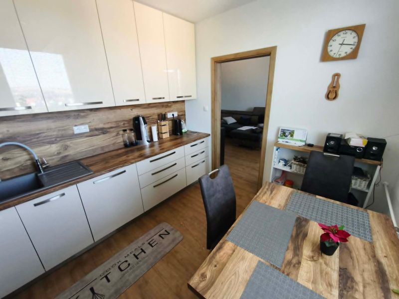 Küche mit weißen Schränken und Holzboden in einer 3-Zimmer-Wohnung.