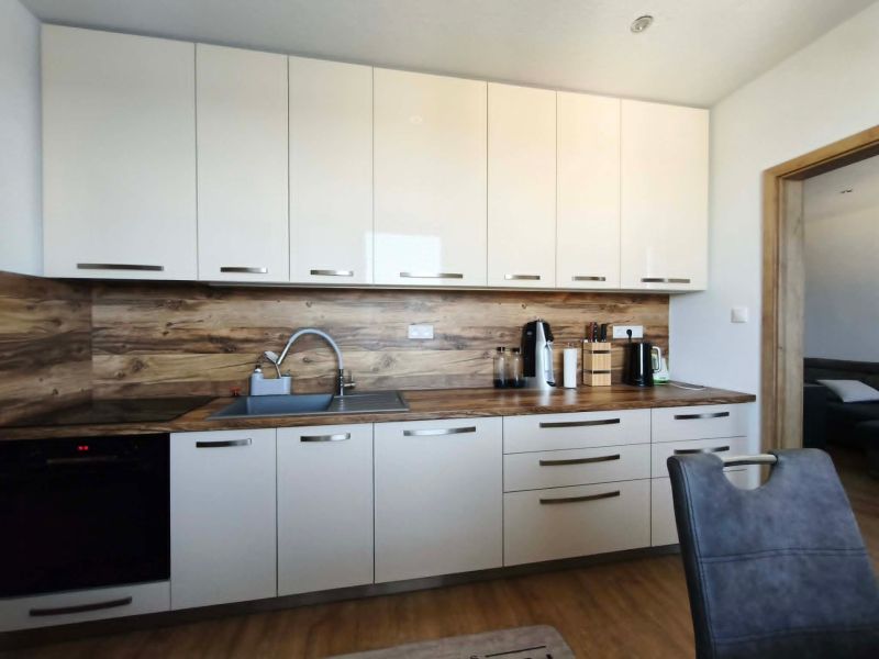 Küche in einer 3-Zimmer-Wohnung mit weißen Schränken und Holzboden.