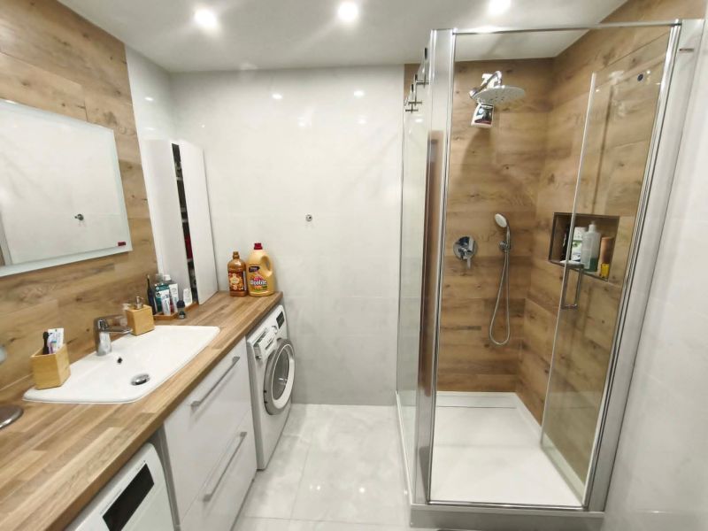 Badezimmer mit Holzboden in einer 3-Zimmer-Wohnung, moderne Ausstattung und Duschkabine.