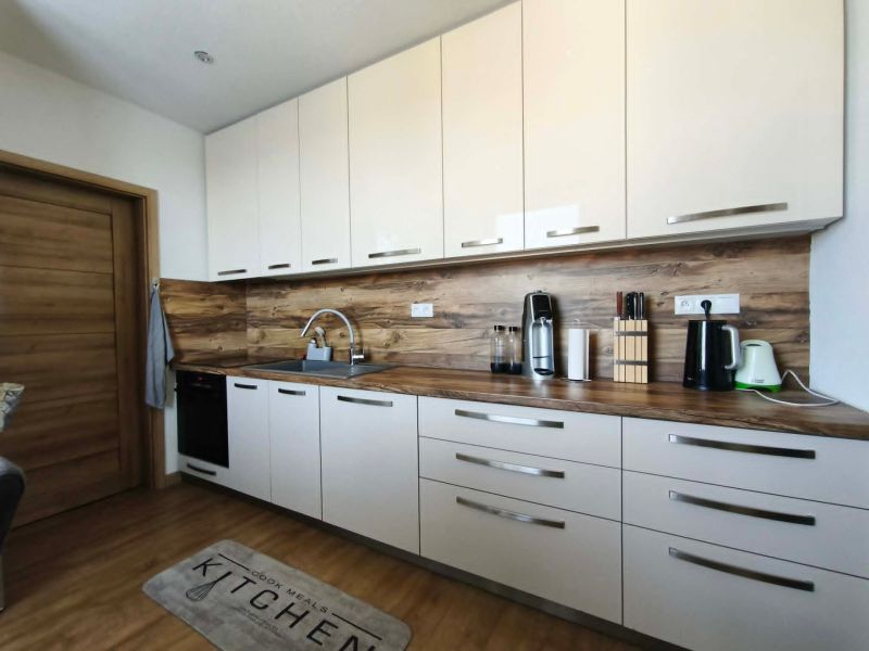 Küche in einer 3-Zimmer-Wohnung mit weißen Schränken und einem Boden in Holzoptik.